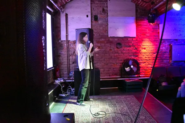 Julia speaking into a microphone on a small stage at "The Dark Side of UX" event.